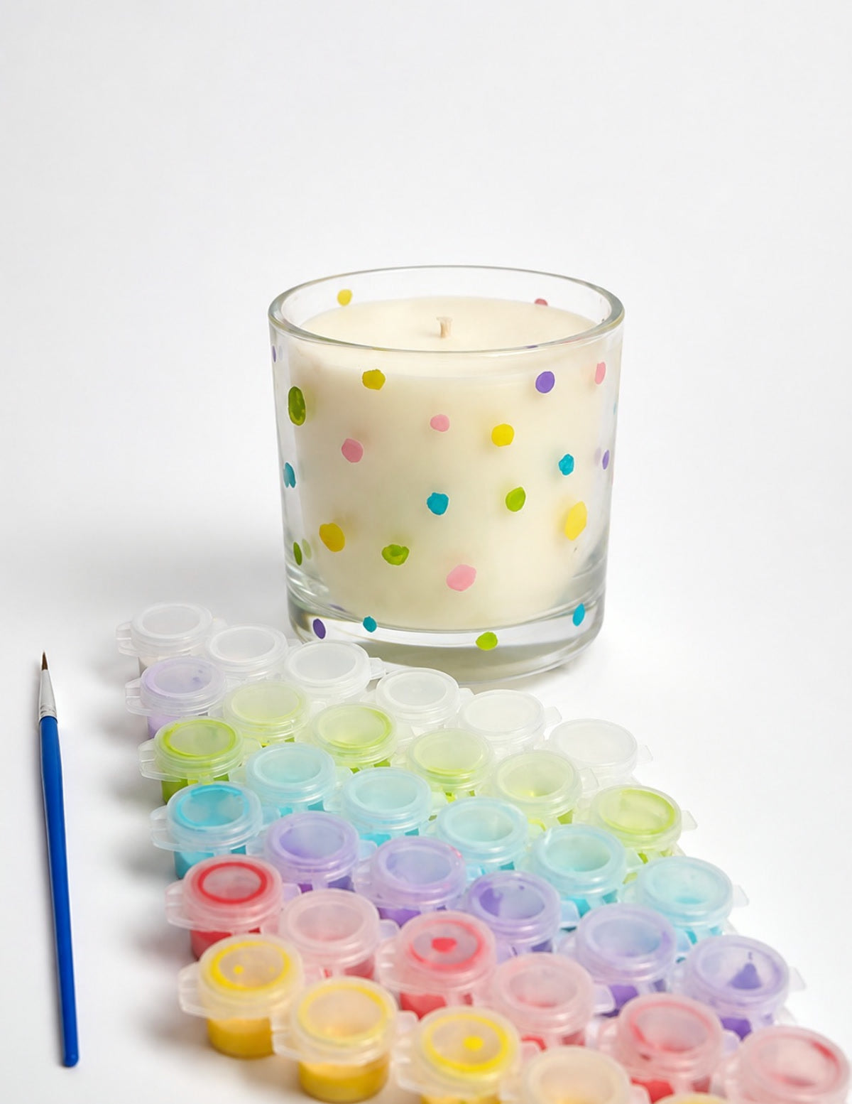 Vela para colorir Blisz Aromas: vidro transparente pintado com bolinhas coloridas, ao lado das tintas e do pincel